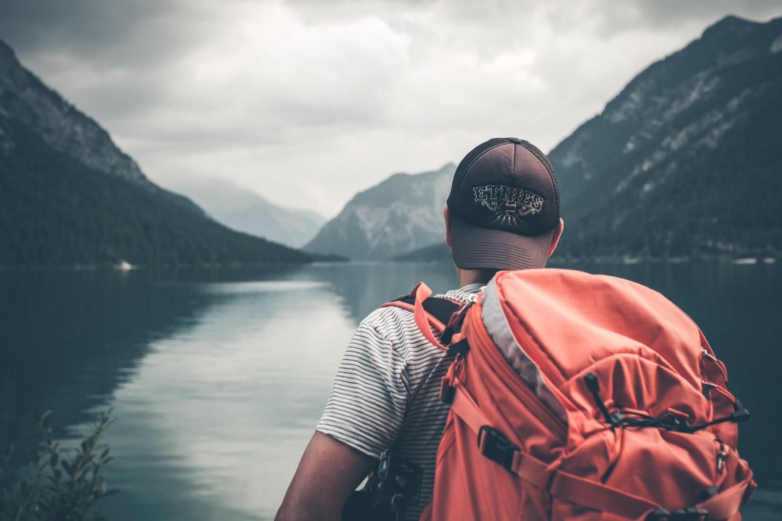 Homme avec un sac à dos regardant un lac entre deux montagnes