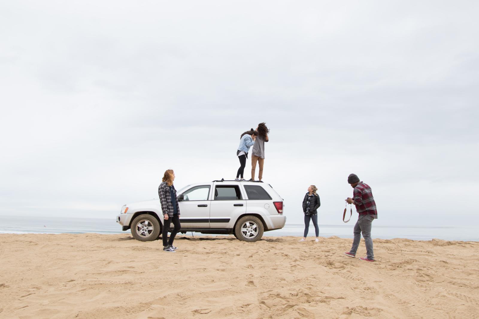 groupe de jeune sur une plage avec une voiture