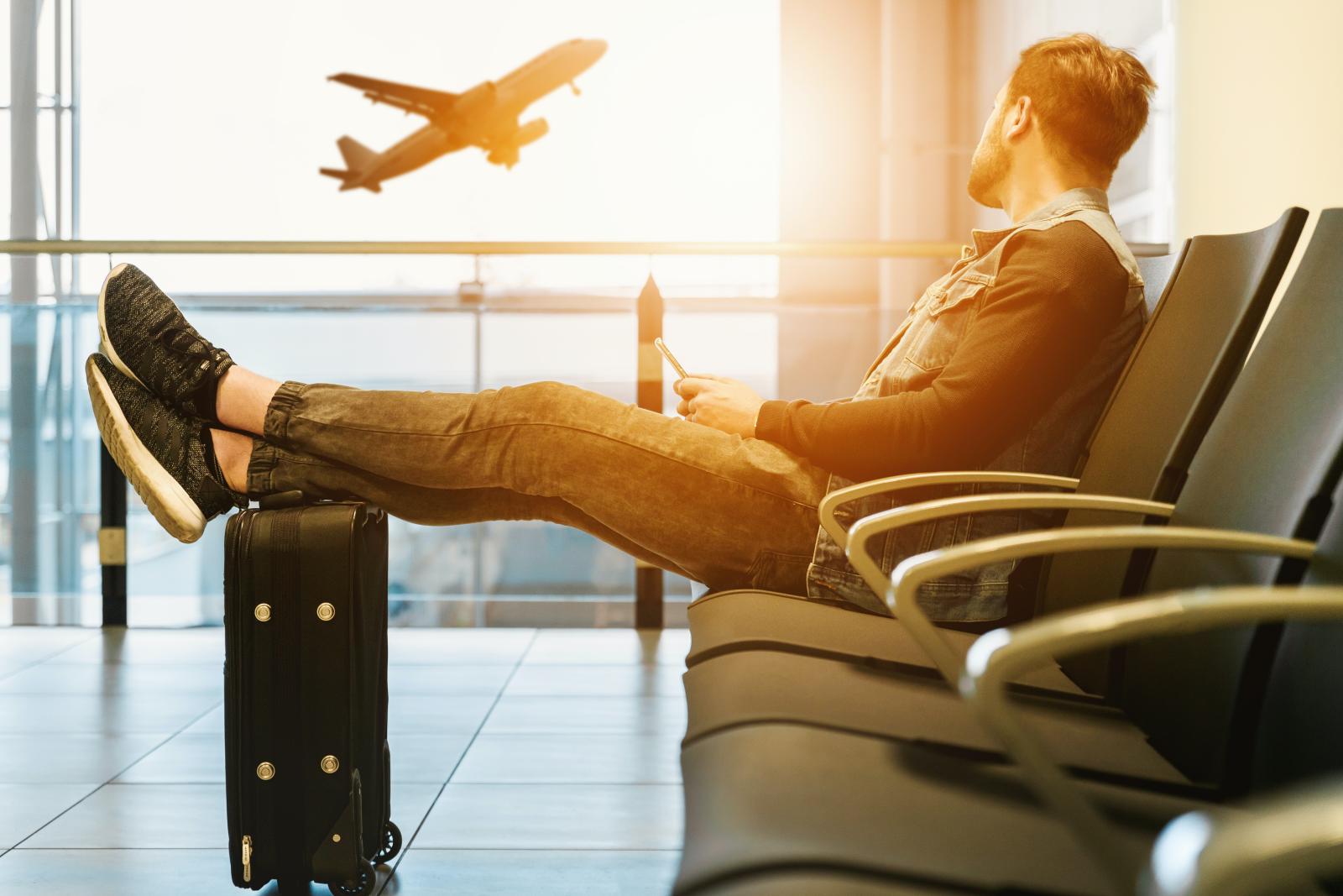 jeune homme assis dans un aéroport regardant un avion décoller