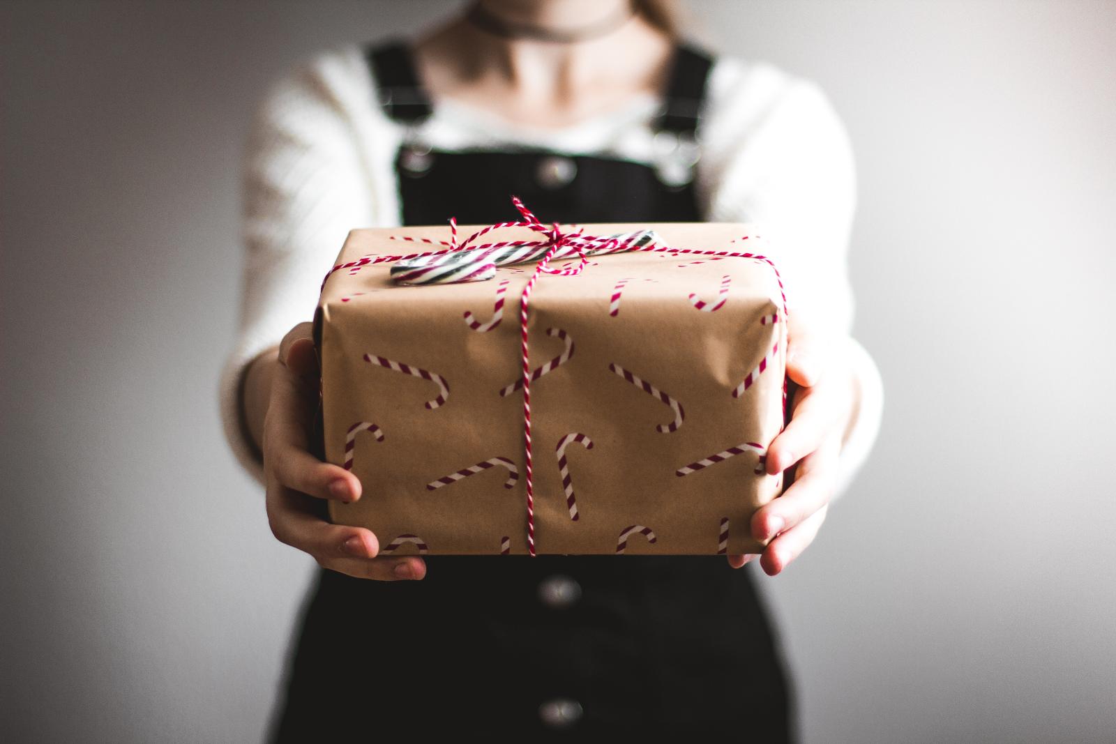 jeune femme tendant un paquet cadeaux marron