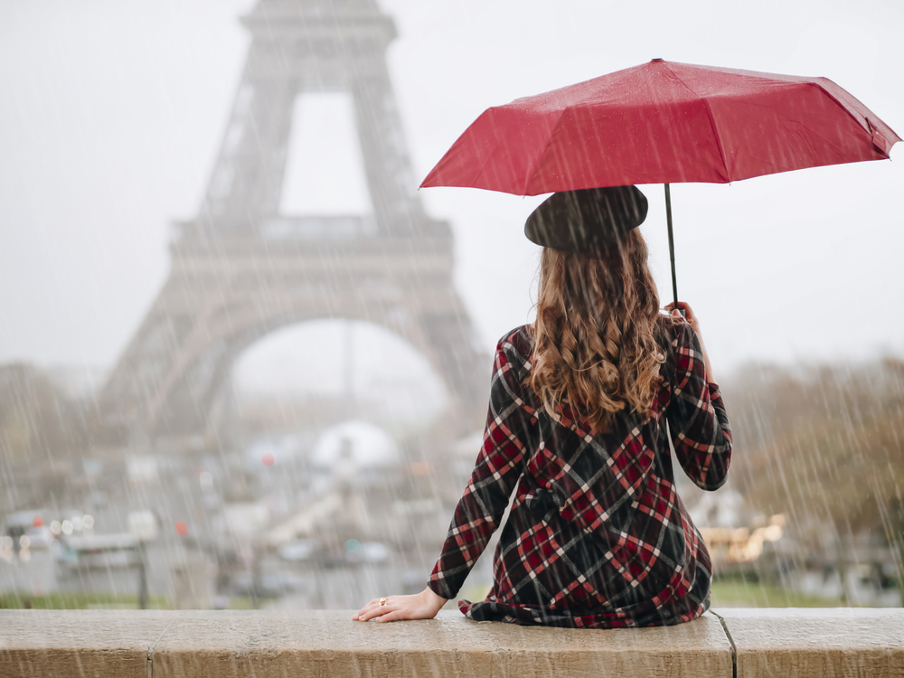 Femme tenant un parapluie devant la tour Eiffel